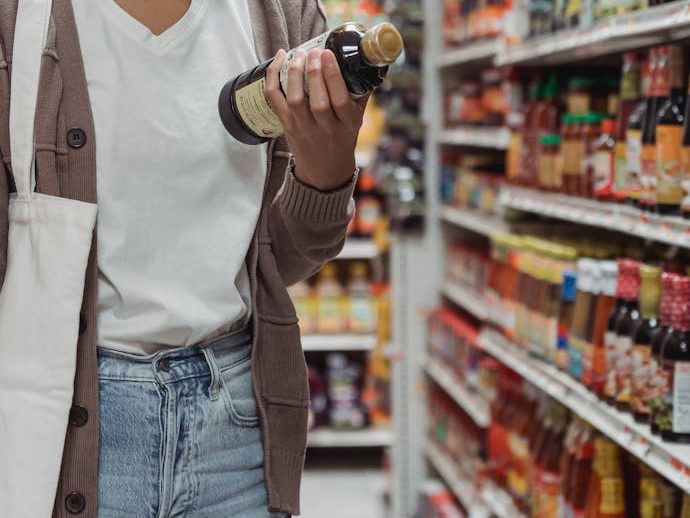 Una mujer lee los ingredientes de una salsa en el supermercado