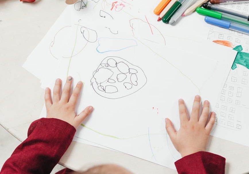 Niño hace un dibujo con pinturas en el colegio