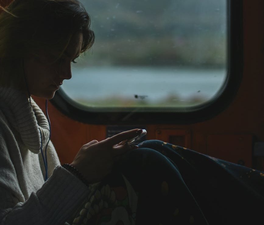 Una mujer mira el móvil delante de una ventana